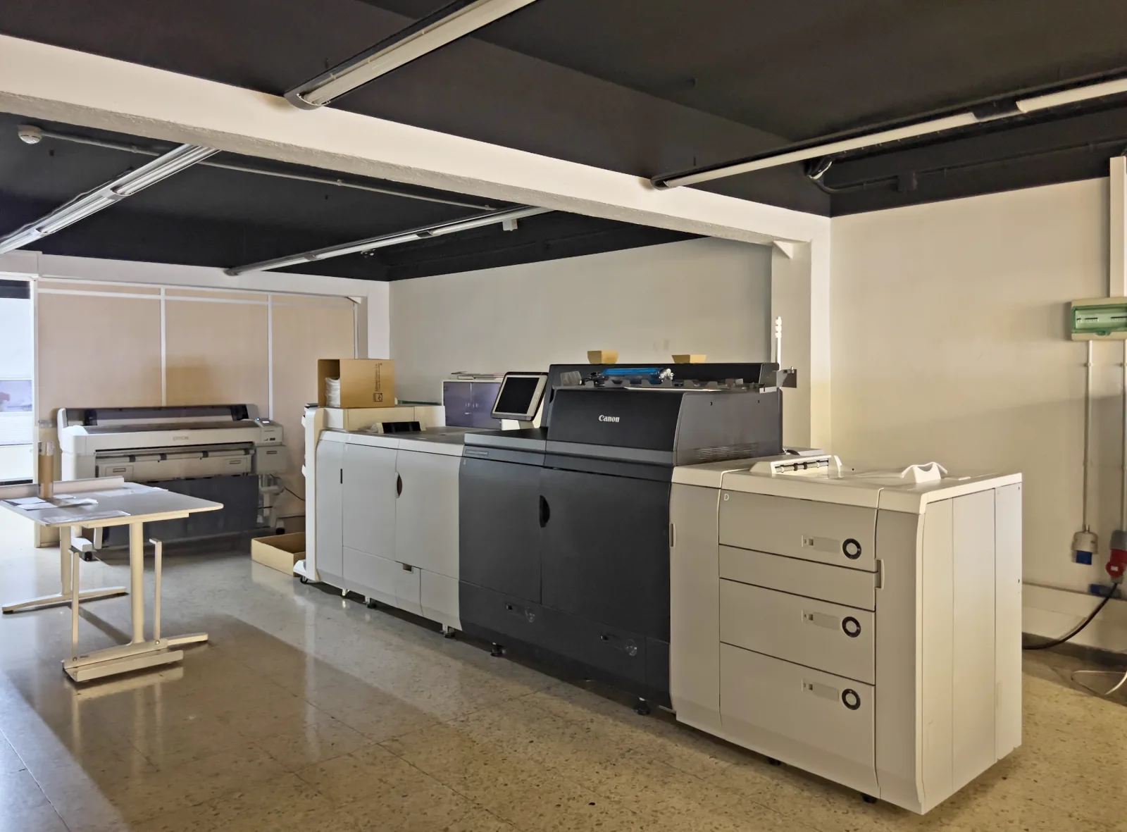 Impressora digital Canon imagePRESS, amb un plotter Epson al fons